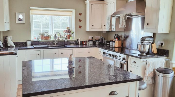 Experience the charm of a Woolverton Somerset kitchen - Cream shaker style with sleek black marble island worktop, impeccably clean and ready for a gourmet cooking session!