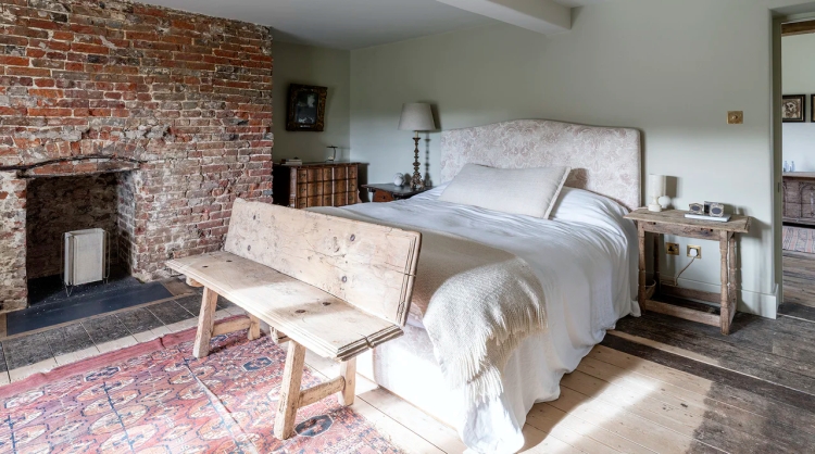 Experience the rustic charm of a vintage farmhouse in Maiden Bradley with a cozy bedroom adorned with beautiful antique furniture and intricate rugs.